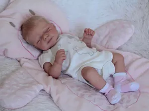 Close-up of a 50cm sleeping reborn baby doll with blonde hair in a rabbit bodysuit