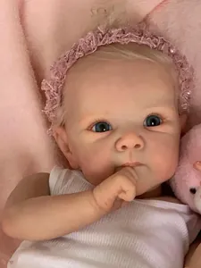 Gros plan d'une poupée Reborn Bettie réaliste avec cheveux blonds et bandeau rose