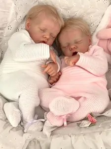 Detailed close-up of twin reborn dolls in pink and white knit outfits on lace bedding