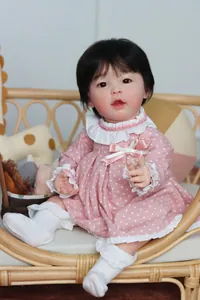 Realistische reborn baby pop van 23 inch in polkadotjurk zittend in een wiegje