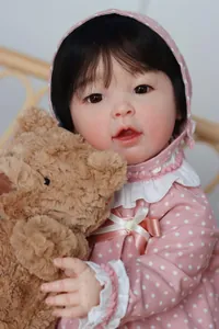 Detail van een 23 inch realistische reborn baby doll in roze polkadot outfit met een beer