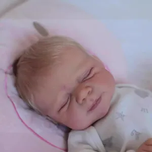 50cm lifelike reborn baby doll sleeping in star pattern onesie on a soft pink cushion