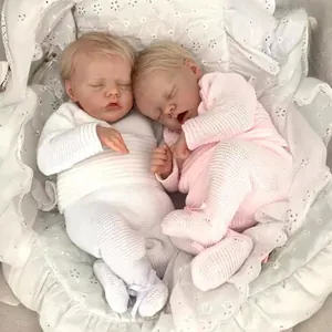 Twin 48cm reborn baby dolls in pink and white knit outfits sleeping in a cradle