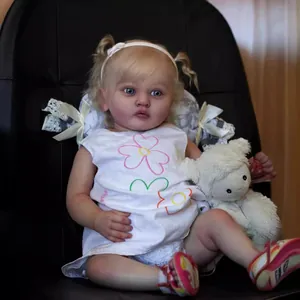 Close-up of realistic 60cm reborn doll with blonde curls and floral white dress