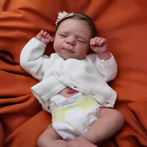 Détail d'une poupée Reborn 19 pouces avec cardigan blanc et bandeau à fleur rose