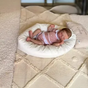 Poupée reborn réaliste de 19 pouces dormant en barboteuse rose sur un coussin blanc