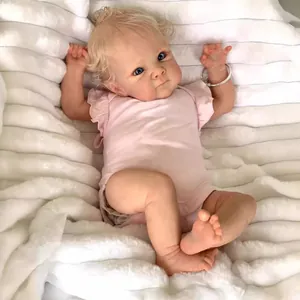 Lifelike 18-inch Bettie reborn baby doll with blonde curls and pink outfit on white rug