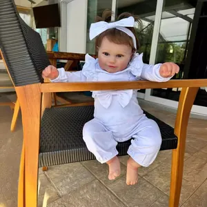 Poupée réaliste Maddie 60cm en tenue blanche à volants assise sur une chaise en bois