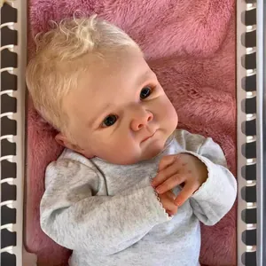 Realistic 18-inch Bettie reborn baby doll with blonde curls on pink plush mat
