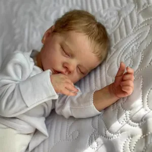 Lifelike 18 inch sleeping reborn baby doll in white bodysuit on quilted blanket