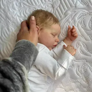 Lifelike 18-inch sleeping reborn baby doll with rooted hair in a white cotton bodysuit