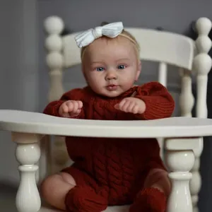 Poupée reborn garçon 24 pouces réaliste en barboteuse rouge sur une chaise haute