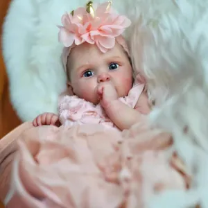 Realistic 19-inch reborn doll with visible veins in pink lace dress and floral headband