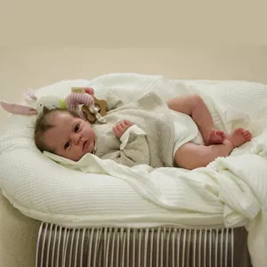 Lifelike 19-inch reborn baby doll with visible veins in a white knit nest with toys
