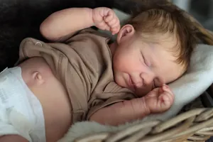 Nahaufnahme einer schlafenden Reborn-Puppe mit braunem Haar in einem Weidenkorb