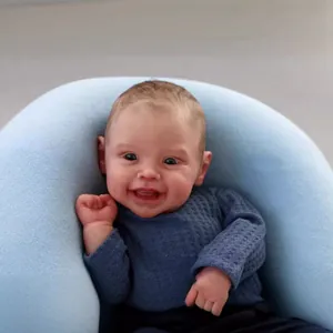 Lifelike 50cm Reborn baby doll Harper wearing navy blue sweater sitting in a nursing pillow