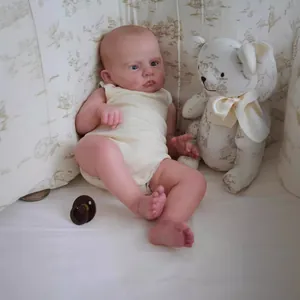 Detailed close-up of a realistic reborn baby doll wearing a yellow romper with a teddy bear