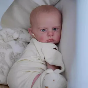 Realistic 60cm reborn baby doll Cameron in cream romper resting on soft cushion