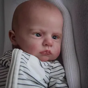 Poupée Cameron reborn de 60cm réaliste en tenue rayée posée sur un tissu doux