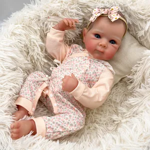 Lifelike 18-inch reborn baby doll Bettie in floral romper lying on soft white plush mat