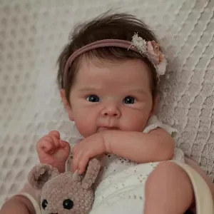 Realistic 18-inch Bettie reborn baby doll with brown hair, lace outfit and plush toy