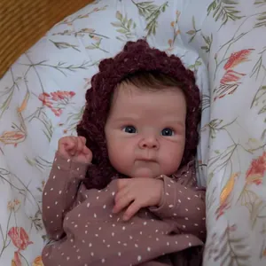 Close-up of 18-inch realistic reborn baby doll with detailed skin and purple crochet hat