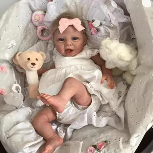 Lifelike 22-inch reborn baby doll in white lace dress with matching embroidery bedding
