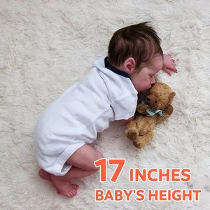 Lifelike 17-inch reborn baby doll sleeping in white onesie on a soft plush rug