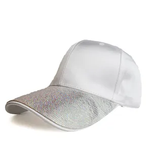 Detail shot of the white satin baseball cap showing sparkling rhinestone brim and texture