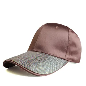 Detail of a brown satin baseball cap featuring a decorative rhinestone-encrusted brim