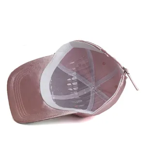 Detailed interior of a pink satin baseball cap featuring mesh lining and metal buckle