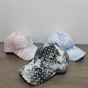 Detailed view of distressed sequin baseball caps in black, pink and blue tie-dye colors