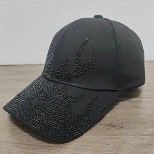 Dettaglio del cappellino in cotone nero con intricati motivi di strass a forma di fiamma