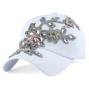 Dettaglio del cappello bianco con ricami floreali e strass scintillanti per donna