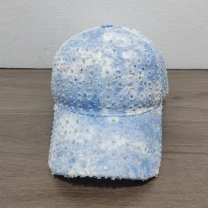Detail of light blue denim baseball cap with distressed frayed edges and silver sequins