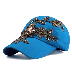 Dettaglio ravvicinato di ricami floreali dorati e strass colorati su un cappello blu navy
