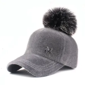 Gray plush baseball cap for women with large black faux fur pompom and metal M logo