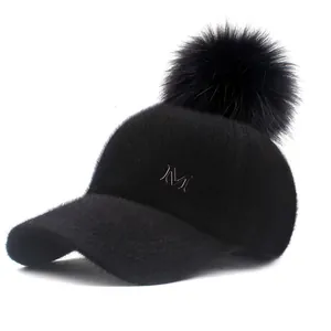 Close-up of black plush baseball cap with fluffy pom-pom and golden metal letter M