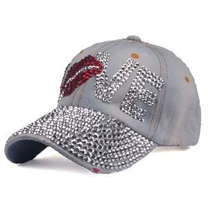 Detailed close-up of light blue denim baseball cap with rhinestone LOVE and red lip pattern