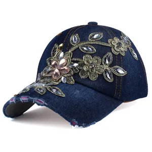 Dettaglio cappello in denim blu scuro con ricamo floreale dorato e strass scintillanti