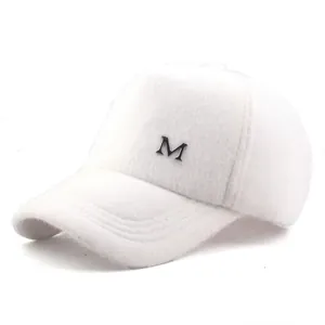 Detail of white plush baseball cap featuring a silver metal letter M emblem