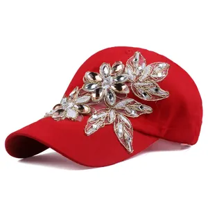 Dettaglio cappello baseball rosso con strass floreali e raffinati ricami in filo d'oro