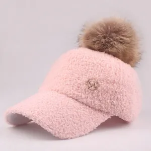 Detailed close-up of pink Sherpa fleece baseball cap with fluffy pom pom and metal M logo