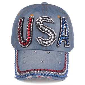 Detailed close-up of USA rhinestone letters on washed blue denim baseball cap surface
