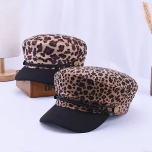 Close-up of leopard print baker boy hat with braided cord and gold side buttons