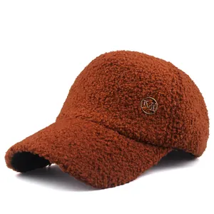Close-up of brown faux shearling baseball cap featuring a golden M logo metal badge