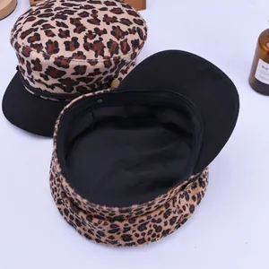 Fashionable leopard print newsboy cap with black brim and decorative metal buttons