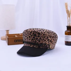 Detail of leopard print baker boy hat featuring black braided rope and gold metal buttons
