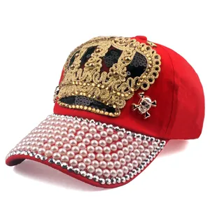 Detailed close-up of red baseball cap with golden crown sequins and pearl brim decorations
