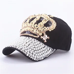 Detailed close-up of a black baseball cap with golden crown sequins and white pearls